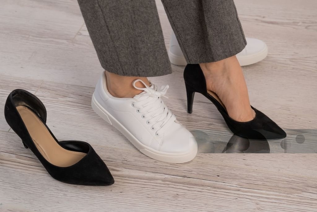 Office Style Diary - Person wearing gray pants with one white sneaker and one black high heel, with another black high heel on the floor nearby.